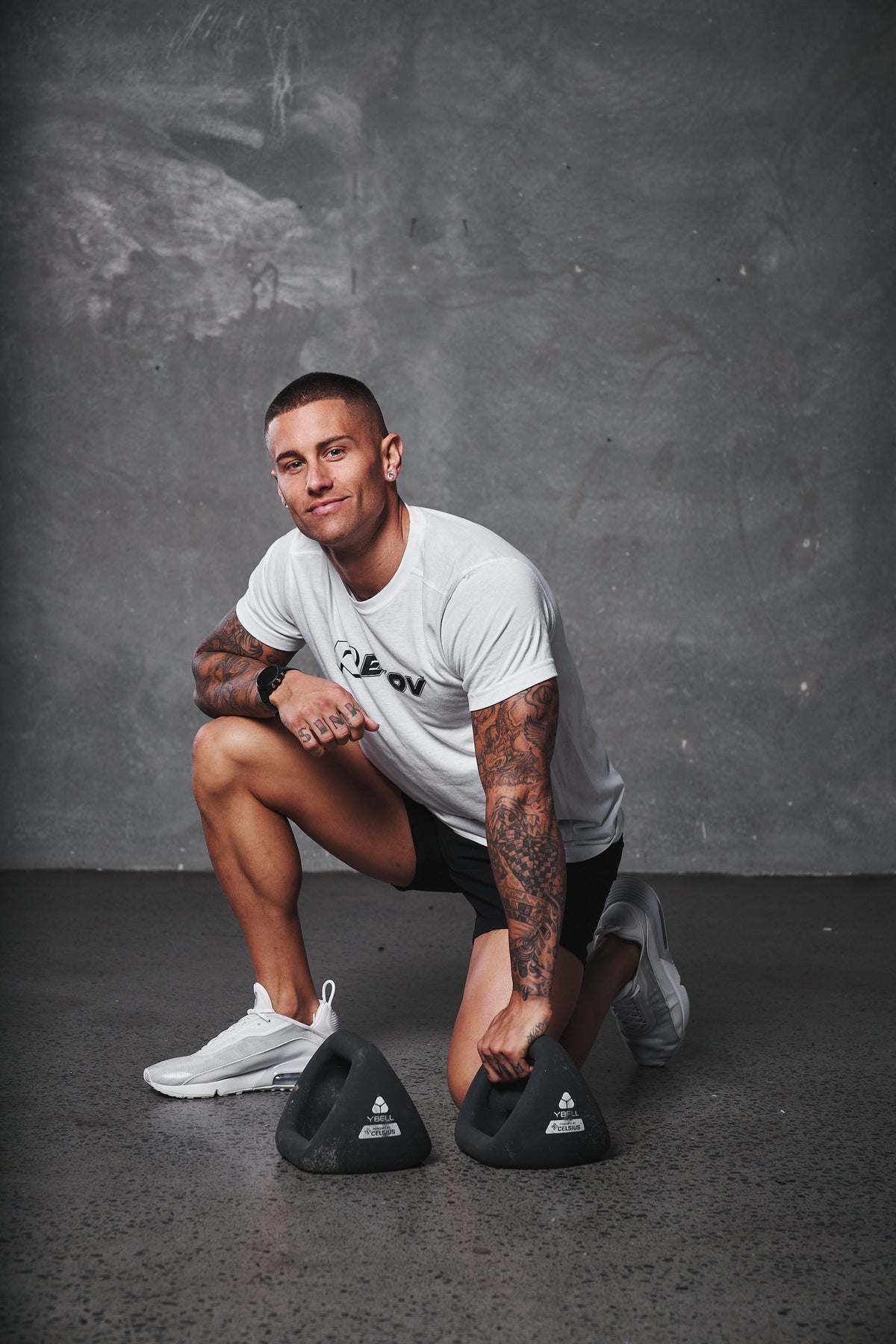 An athlete in a Recov training shirt kneeling beside training weights