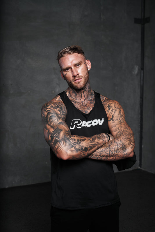 An athlete in a Recov training singlet with arms crossed