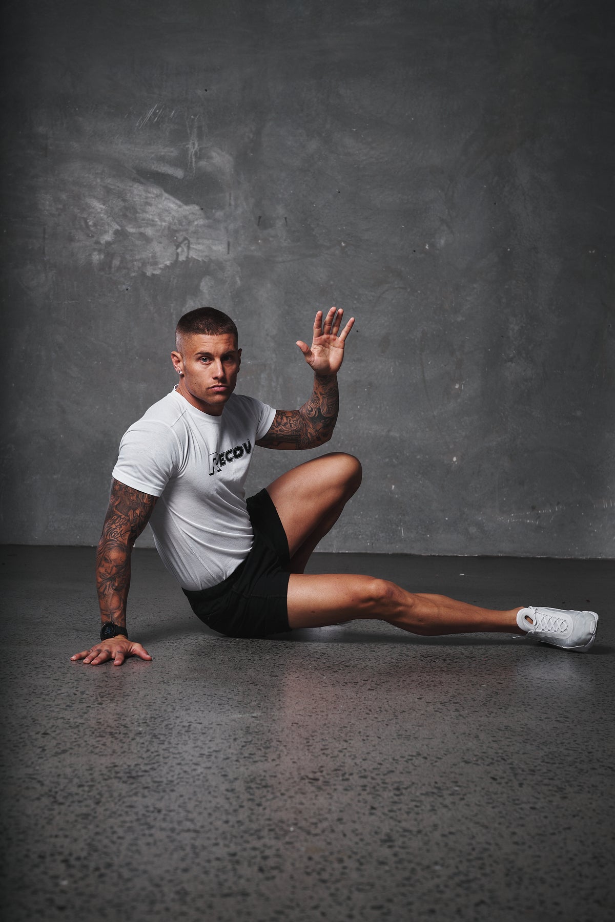 An athlete in a Recov training shirt stretching on the gym floor